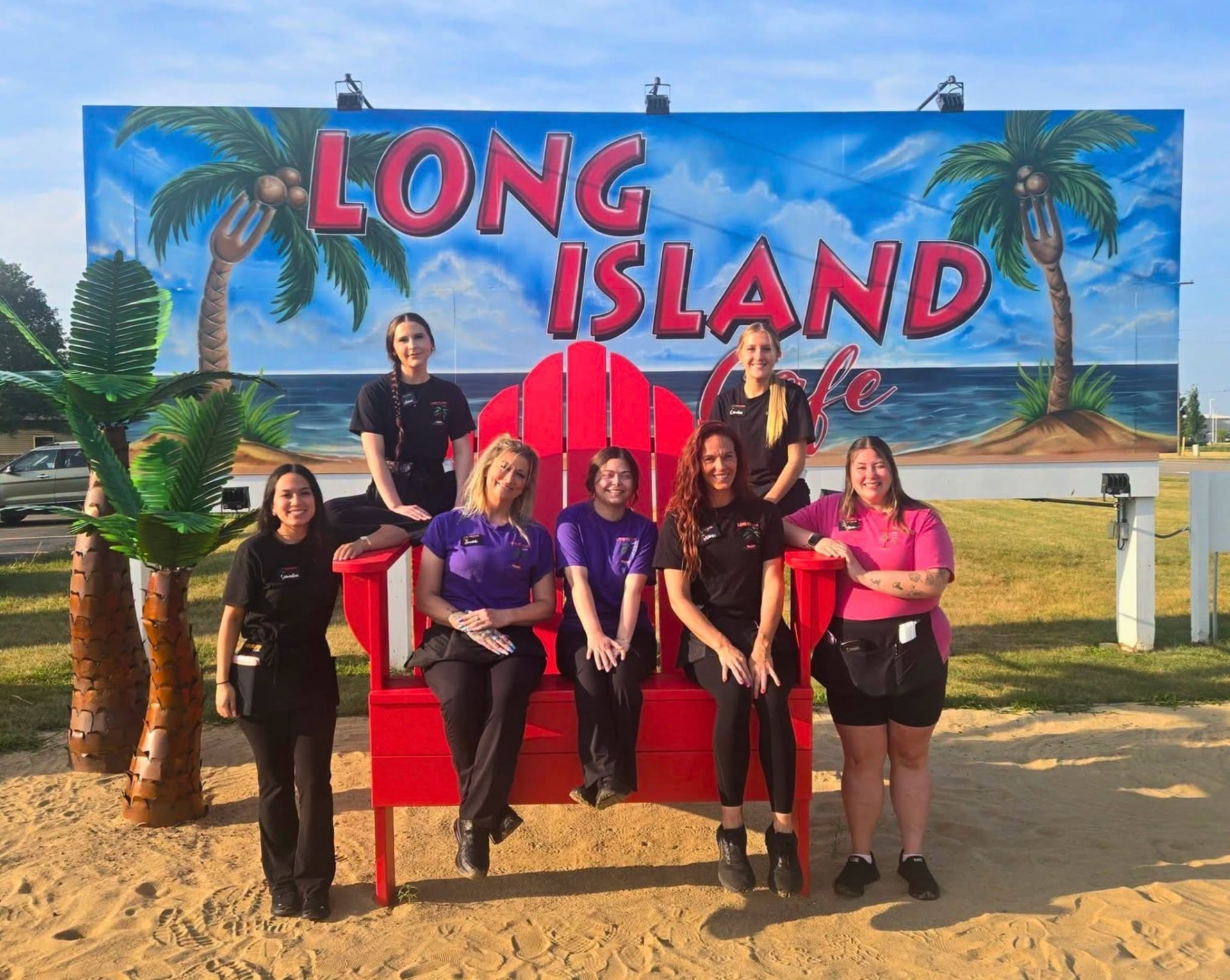 The Long Island Cafe team in front of the cafe sign